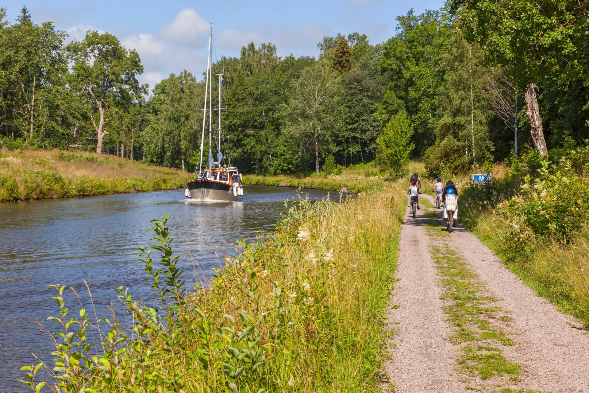 Cyclists and a boat in an idyllic canal landscape