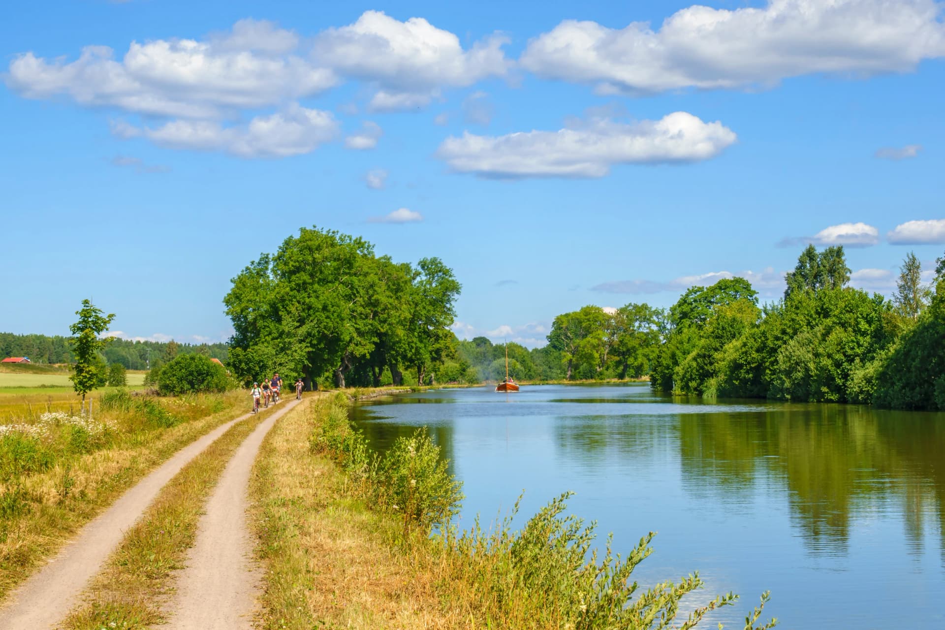 Dirt road at a canal with a boat and cyclists