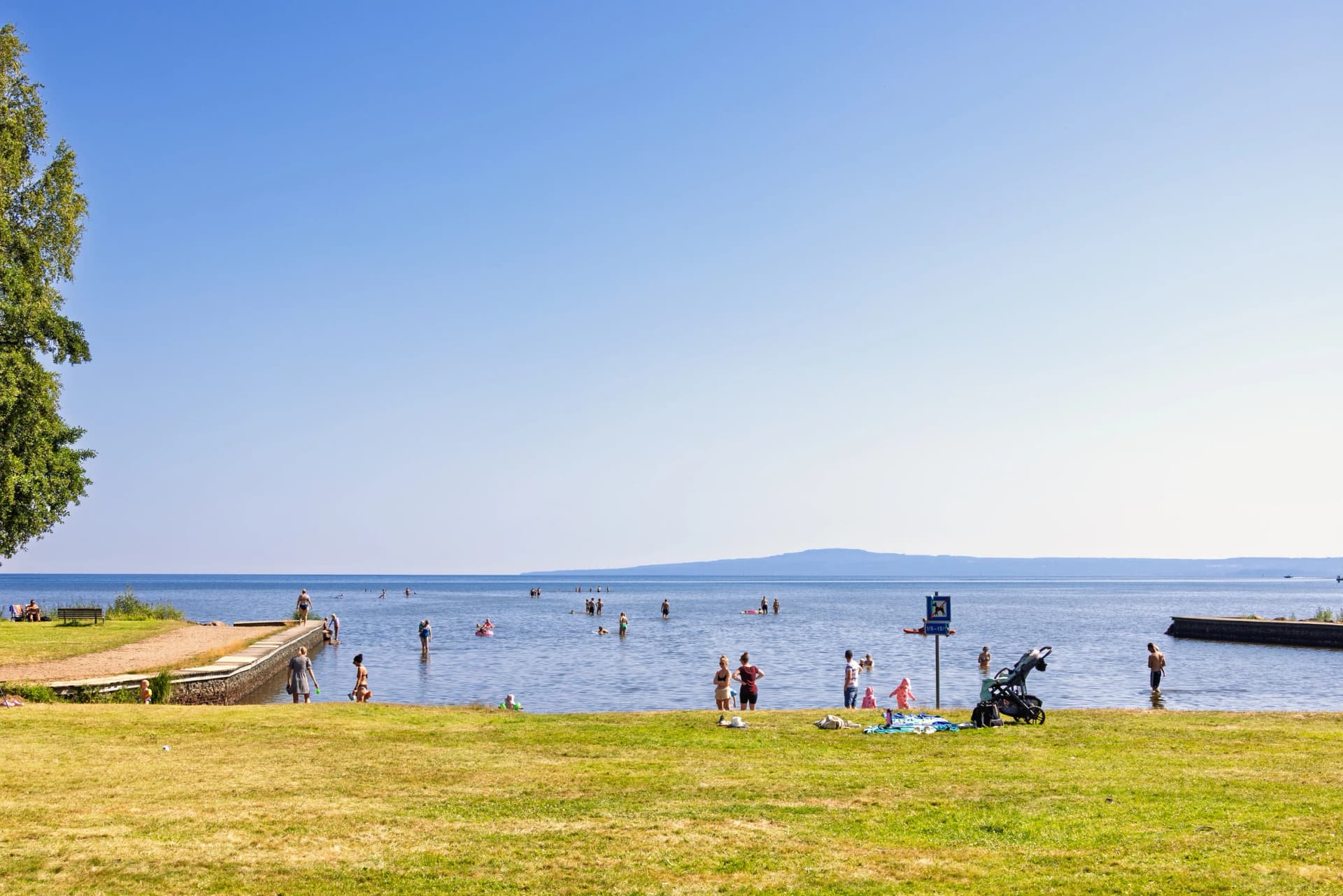 Bathing place with swimmers on a hot summer day at Lake Vänern below Kinnekulle