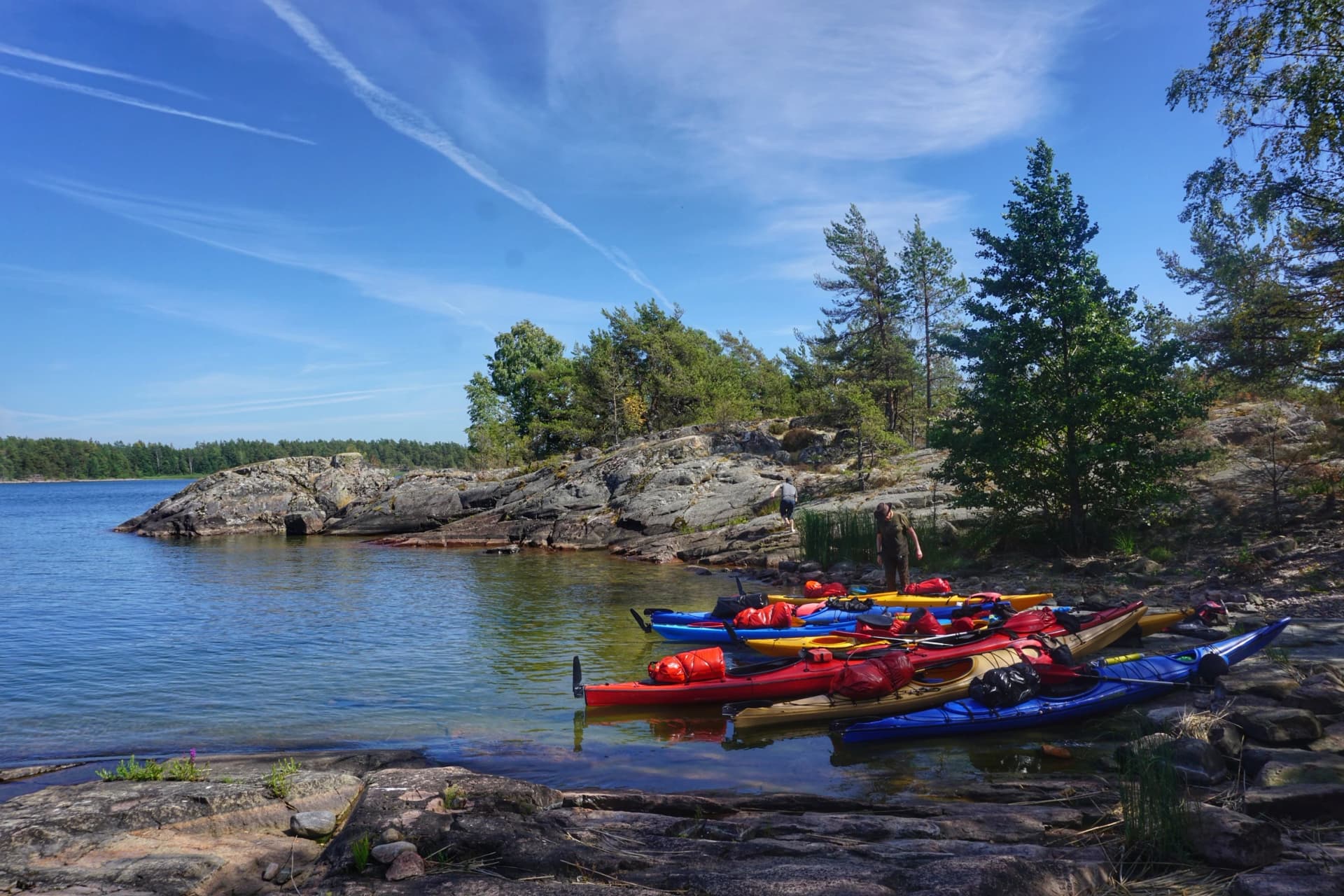 Kayaks pulled up on the rocky shore of a Swedish lake