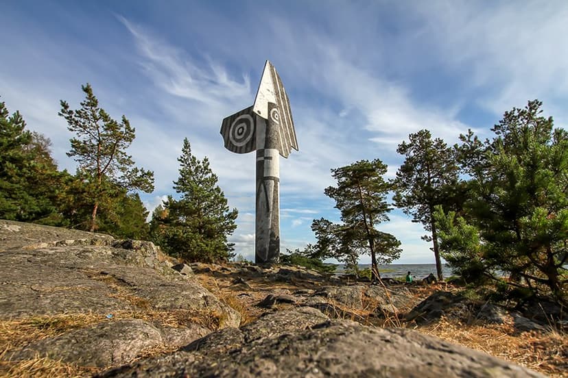 Picasso sculpture in Kristinehamn surrounded by pine trees and rocky ground near water