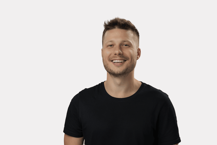 Smiling man wearing a black t-shirt against a plain white background.