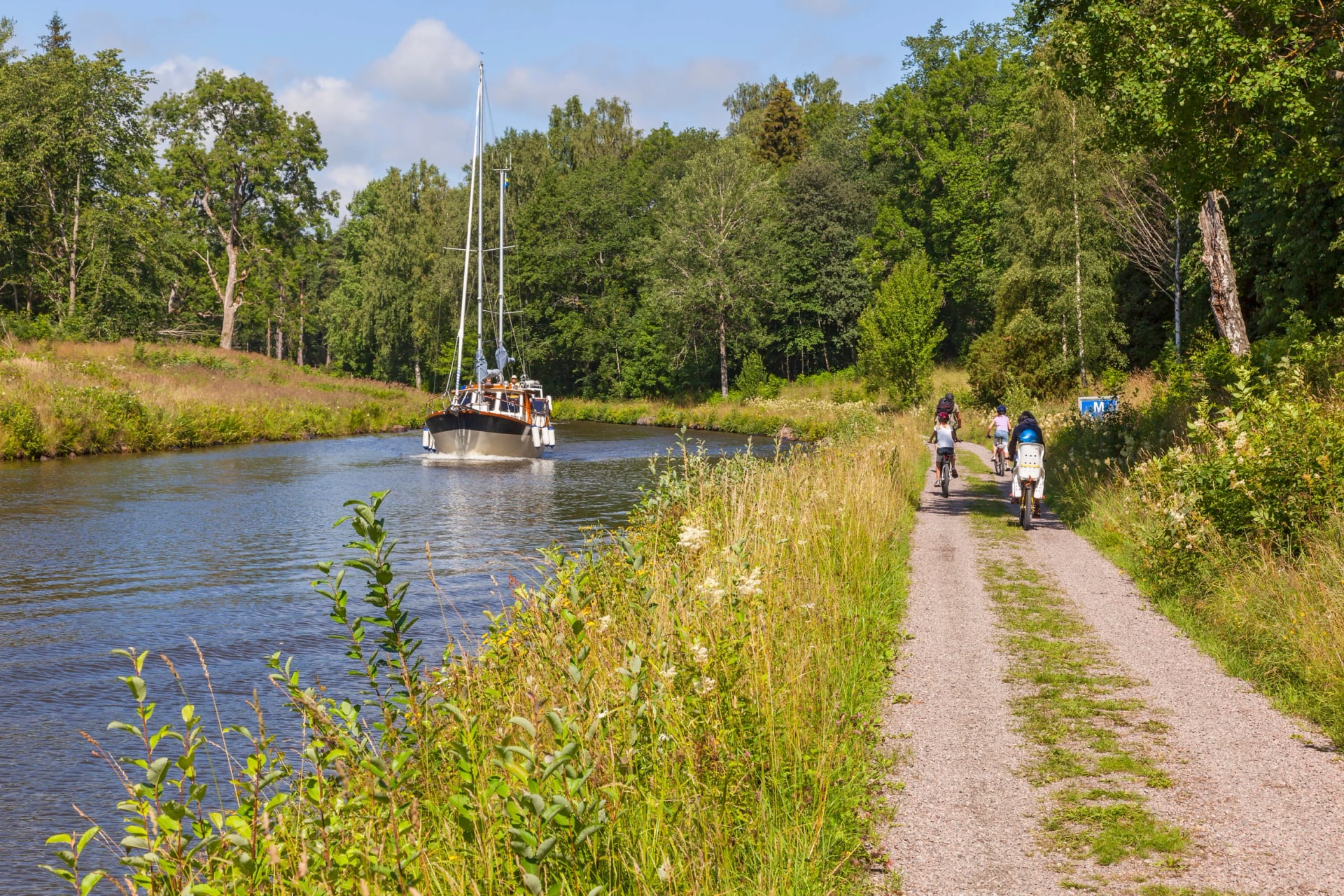 Cyclists and a boat in an idyllic canal landscape