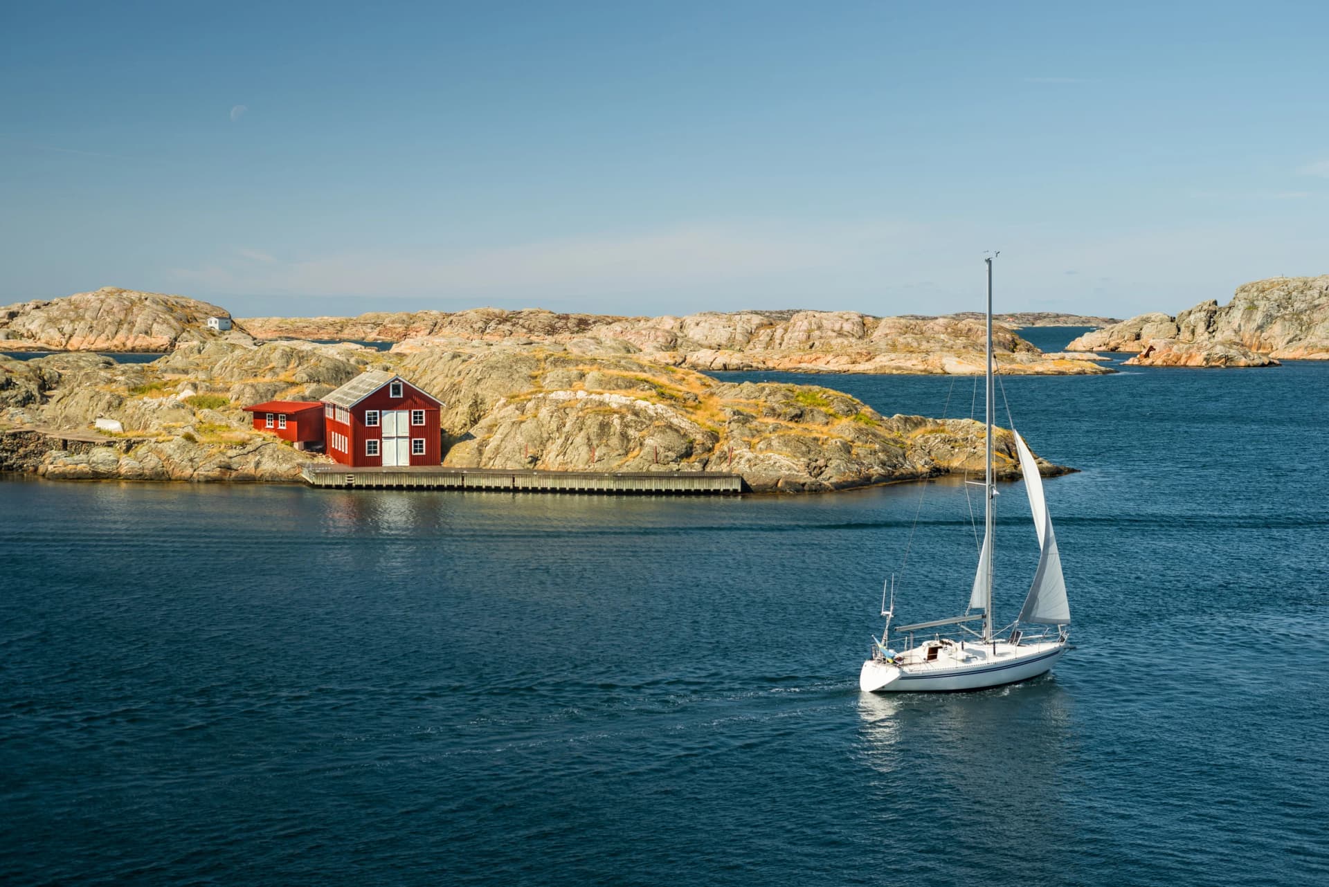 Sea landscape with sailboat and rocky coastline on the South of Sweden. Southern coastline of Sweden with view at sailing-ship and rocky islands.